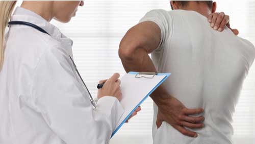 Young female doctor examines man's back injury for maximum medical improvement