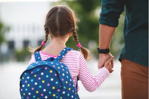 Dad leading little girl to school, parallel parenting concept