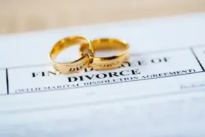 Two gold wedding rings rest on top of a divorce document titled "Final Decree of Divorce," a poignant reminder of a chapter closing. If you find yourself in need during such challenging times, Charlotte Family Lawyers are here to offer compassionate and expert guidance.