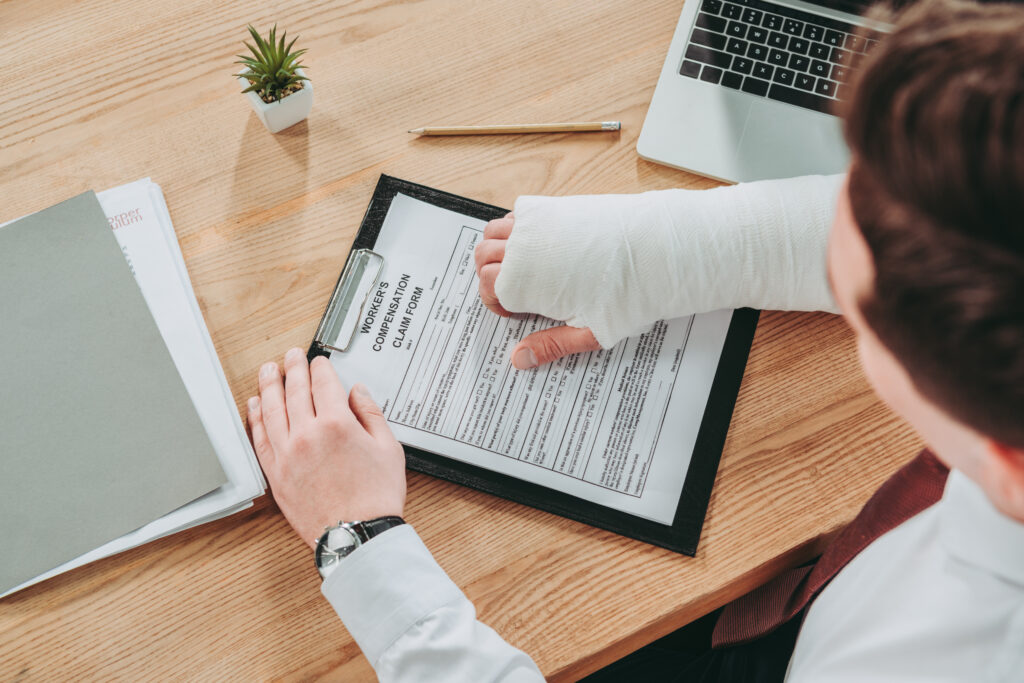 Overhead view of man filling out work injury claim form.