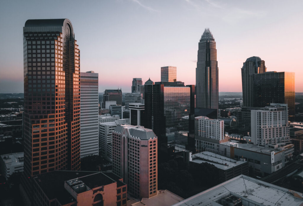 City skyline at dusk with tall buildings reflecting the sunset.