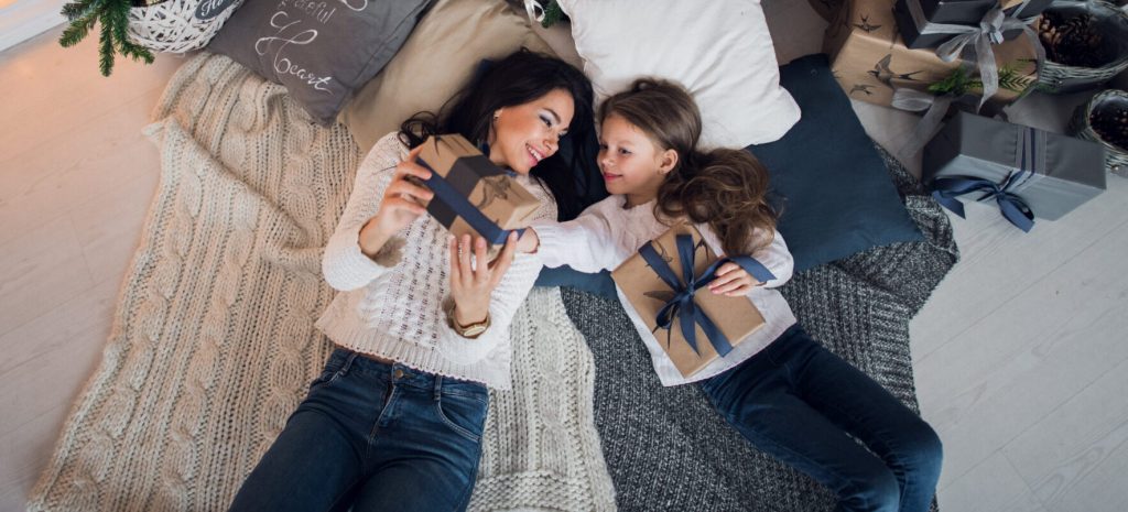 Mother and daughter lying together while exchanging wrapped gifts, representing family relationships and parent-child bonds in Charlotte family law matters.