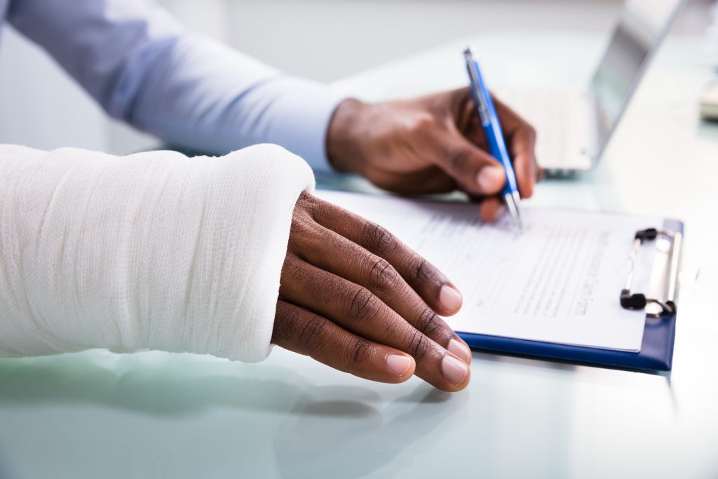 A person filling out paperwork for a workers' comp claim.