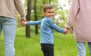 Small boy holding hands of his parents, to show relationship of Child Custody for Unmarried Parents in Charlotte.