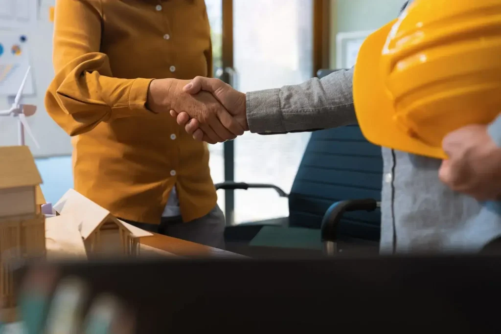 Workers and employer representatives shaking hands during a workers’ compensation settlement or workplace injury resolution discussion.