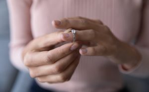 Woman removing wedding ring from finger as thinking divorce is coming and needing to consult with Charlotte Pre-Divorce Planning Lawyer.