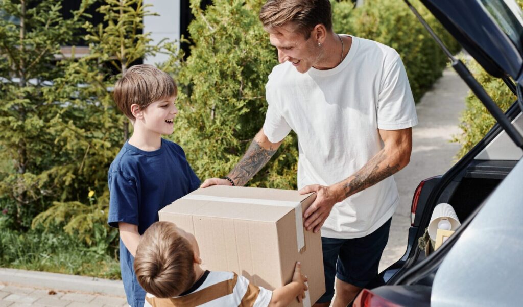 Father helping children load boxes into a car during a family move or custody exchange in Cabarrus County.