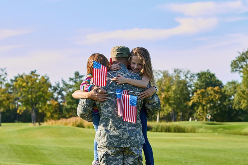 A military service member hugging his children.