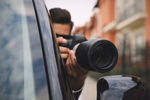 Private detective with camera spying from car, focus on lens