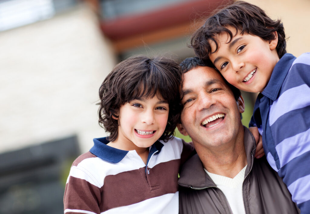 A father and his two sons hugging and smiling after getting help from experienced LGBT family law lawyers.