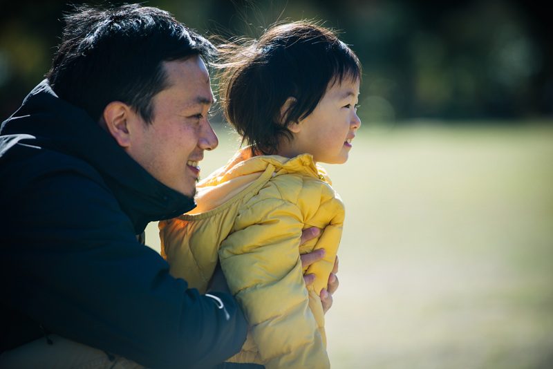 Happy and playful Japanese father and son in a park in Denver