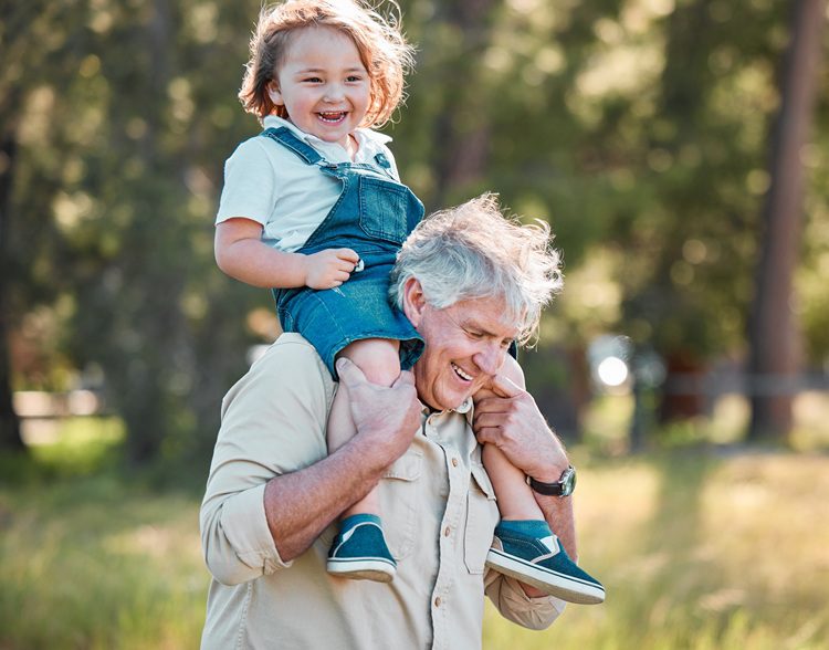 Grandfather carrying his grandchild on his shoulders while walking outdoors, illustrating the strong family connection involved in NC grandparent custody and visitation cases.