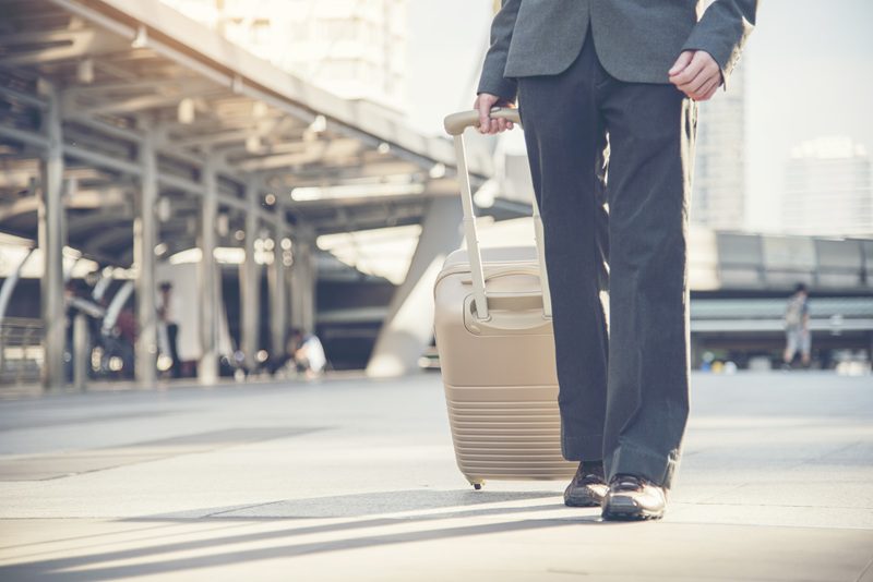 Business traveler pulling a suitcase through a transit area while traveling for work purposes.