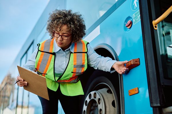 A city transport employee inspecting their bus.