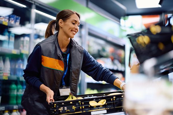Supermarket employee stocking merchandise, representing risk for retail workplace injury