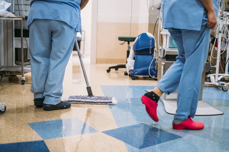 Hospital workers cleaning a room after a medical incident. Chemicals used for sanitizing and disinfecting in this kind of environment could pose a chemical exposure injury risk.
