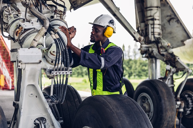An airport worker looking at landing equipment.