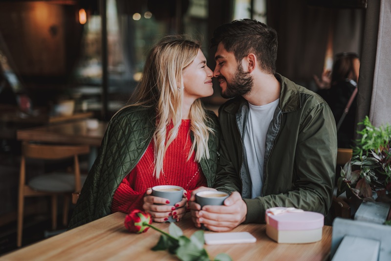 A couple is having a sweet, intimate moment while on a date in the coffee shop.