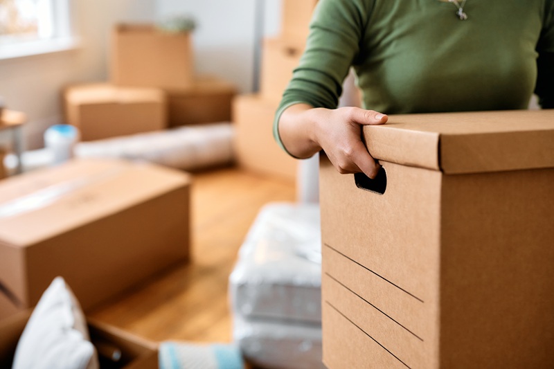 Close up of woman carrying cardboard box while moving out of her home.